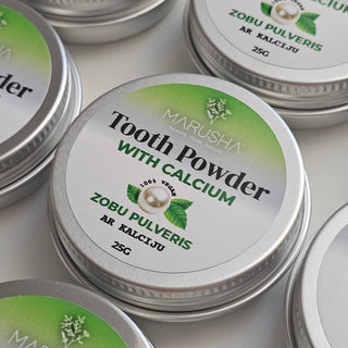 Multiple tins of Marusha Tooth Powder with Calcium on a light background