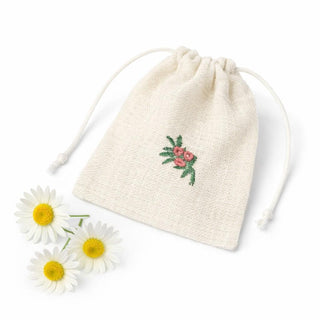 Drawstring bag with floral embroidery on a white background with daisies.