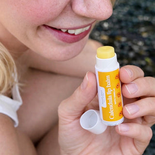Person holding a Calendula lip balm with a blurred background