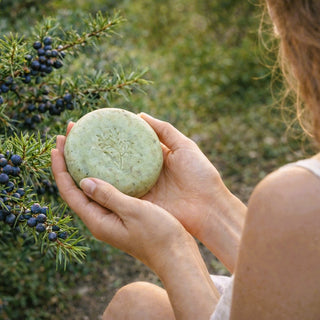 Sieviete tur rokās dabīgas kadiķa ziepes pie kadiķogu koka