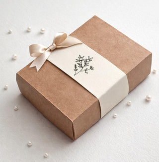 Brown gift box with white ribbon and decorative label on a light background