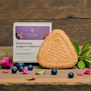 Marusha shampoo bar with packaging on a wooden surface with flowers and berries.