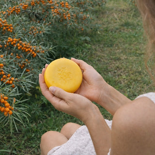 sieviete tur rokās Marusha dabīgās smiltsērkšķu ziepes pie smiltsērkšķu ogu dārza