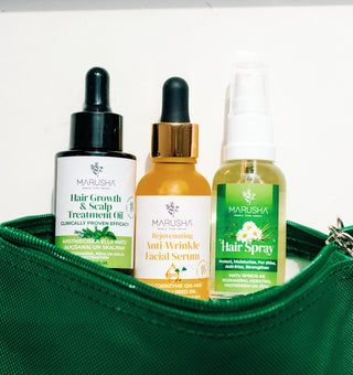 Three MARUSHA hair care products arranged in a green zip pouch: a black dropper bottle of Hair Growth & Scalp Treatment Oil, an amber bottle with a gold cap of Rejuvenating Anti Wrinkle Facial Serum, and a green spray bottle of Hair Spray with Rosemary and Silk.
