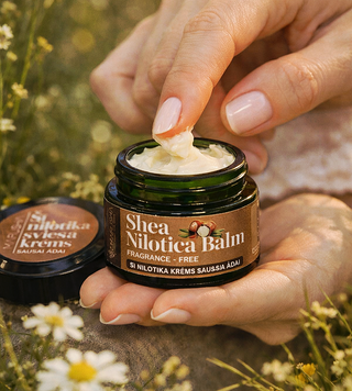 Roku krēms sausai ādai ar šī sviestu un E vitamīnu sievietei rokās ar atvērtu pudelīti